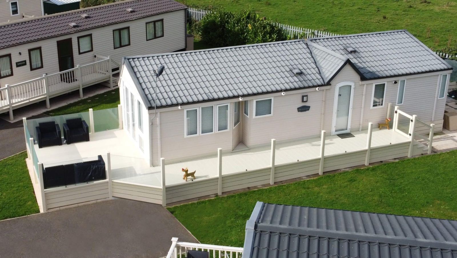 Cream holiday home with a wraparound sundeck, glass balustrade and skirting